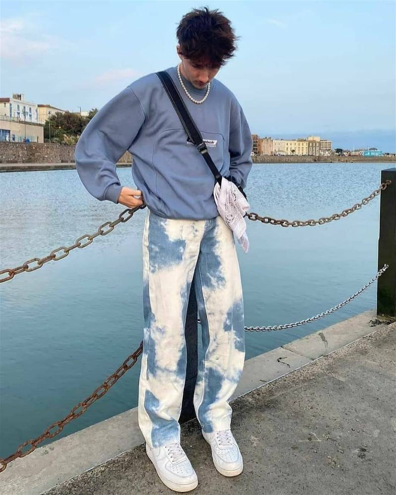 garoto com calça jeans estilizada e moletom azul estilo urbano