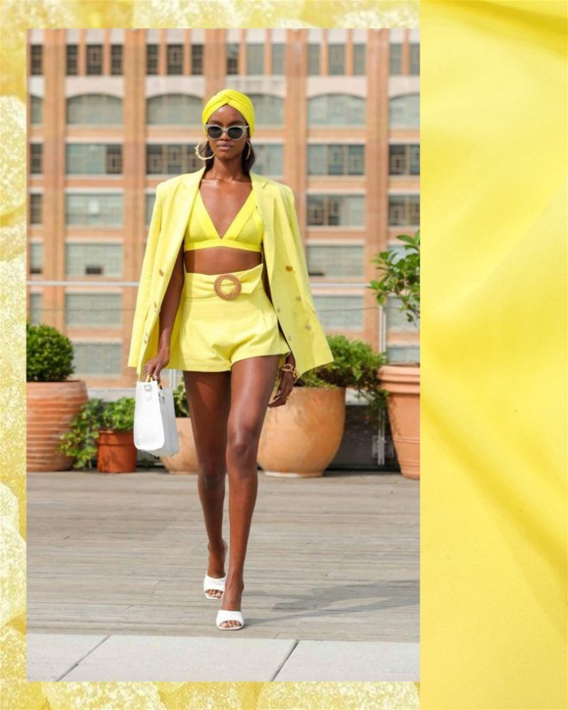 mulher usando shorts, top e jaqueta na cor amarelo manteiga e detalhe do tecido viscose